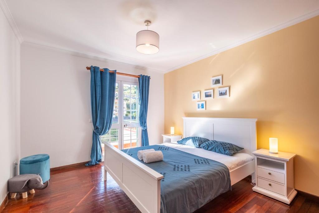 a bedroom with a bed with blue sheets and a window at Casa Vista Mar by GALMI in Calheta