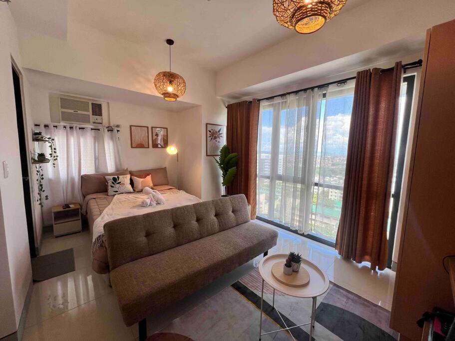 a living room with a couch and a large window at Studio Unit Viceroy Residences McKinley Hill BGC in Manila