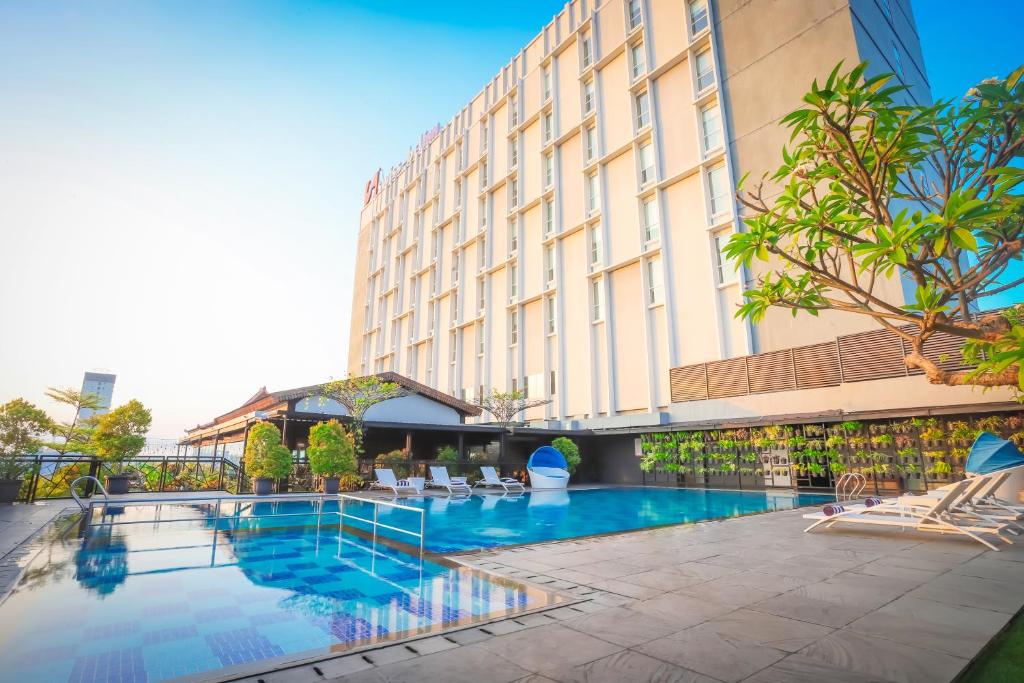 a hotel with a swimming pool in front of a building at Swiss-Belinn Saripetojo Solo in Solo