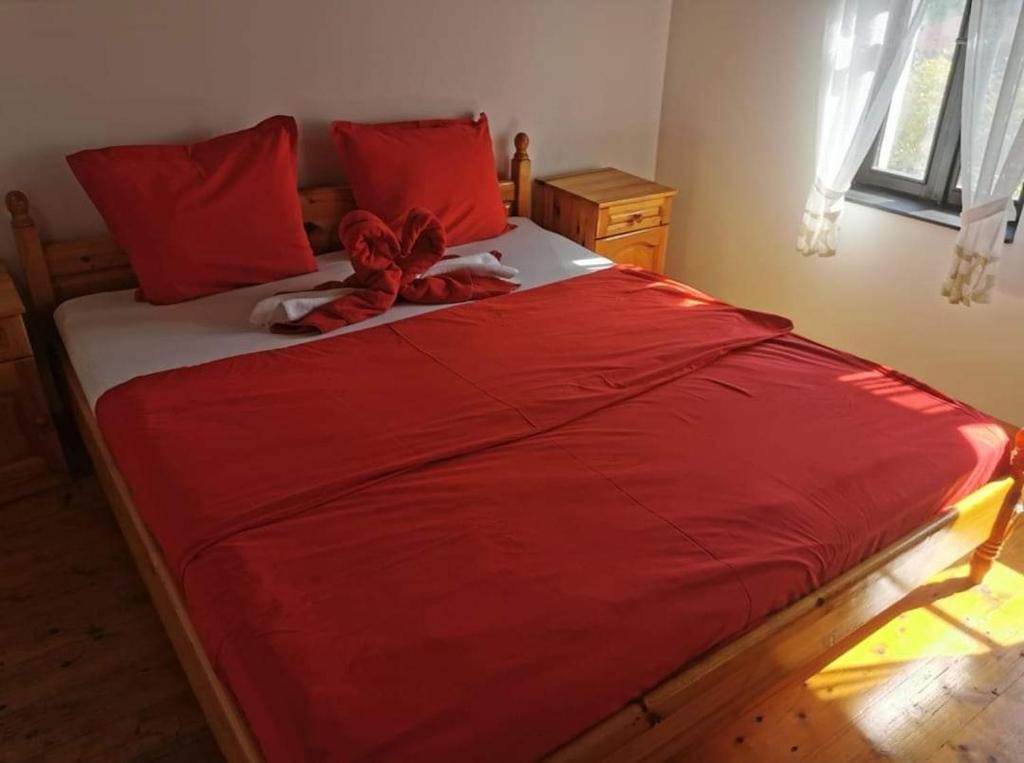 uma cama com lençóis vermelhos e um laço vermelho em АРНАТА КЪЩА em Yakovtsi