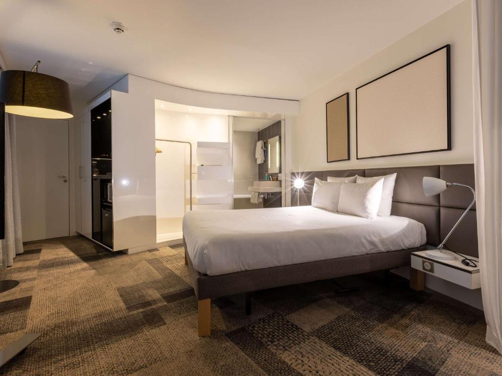 a bedroom with a large white bed and a lamp at Novotel Suites Paris Expo Porte de Versailles in Paris