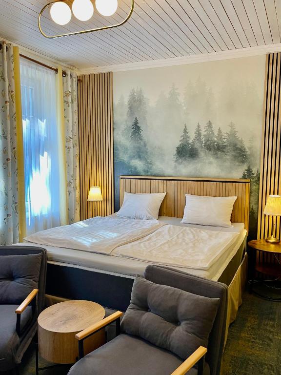 sypialnia z dużym łóżkiem i 2 krzesłami w obiekcie Penzion Kokorin Forest Villa w mieście Konrádov