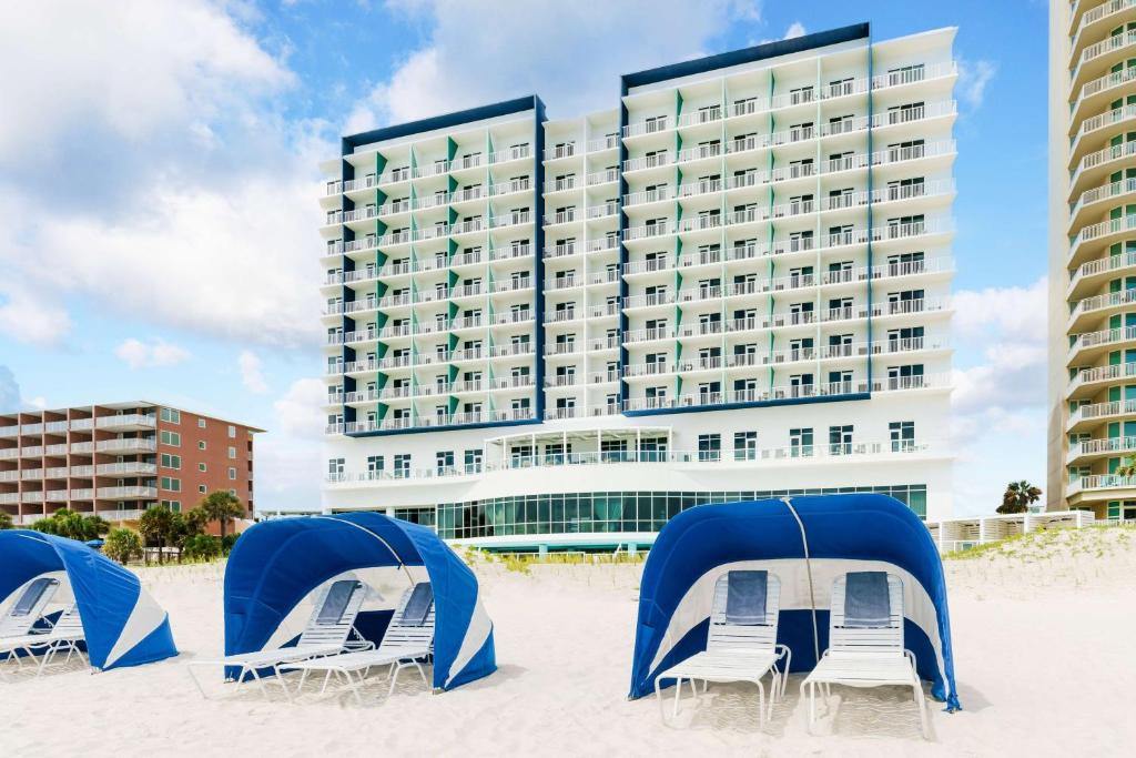un hotel sulla spiaggia con sedie e tende di Hyatt Place Panama City Beach - Beachfront a Panama City Beach