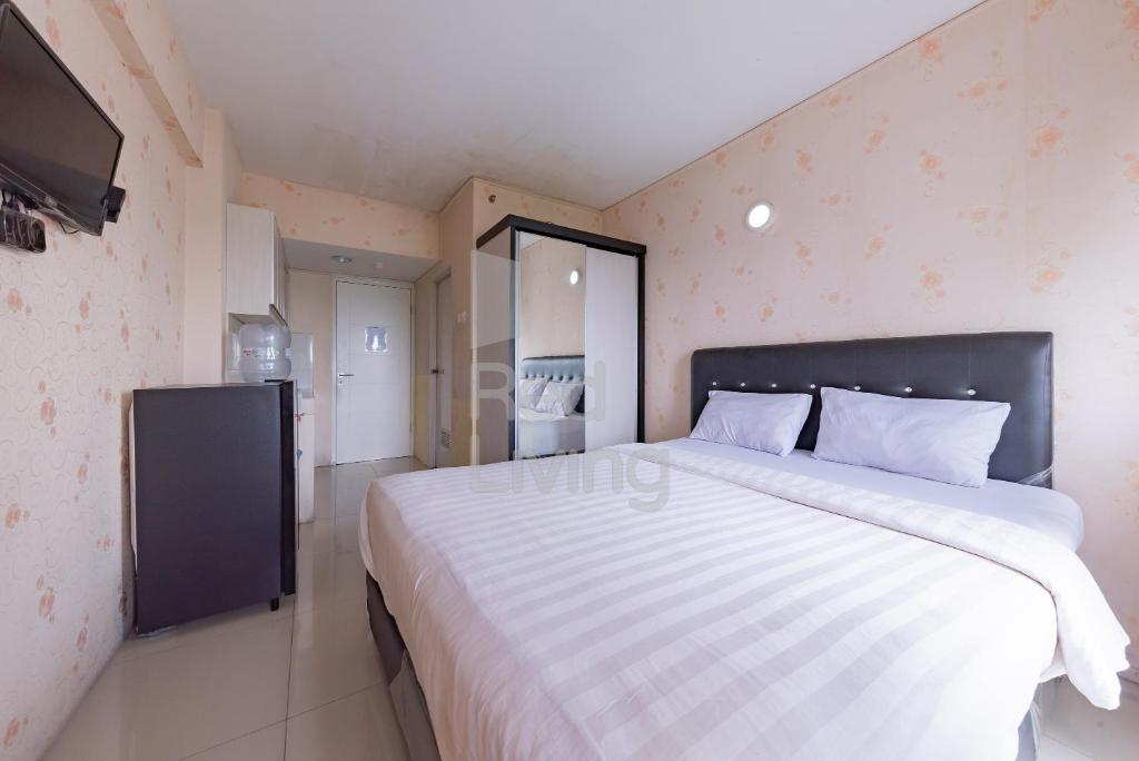 a bedroom with a large bed and a television at RedLiving Apartemen Grand Sentraland - Dragon Apartel Tower Pink in Karawang