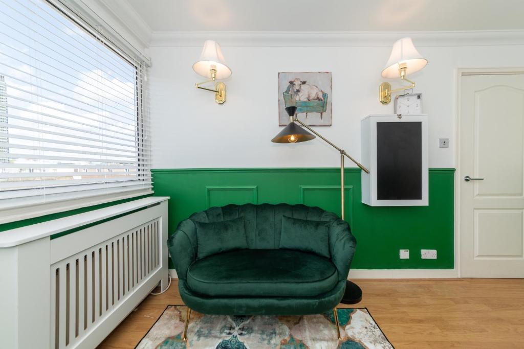 - une chaise verte dans une pièce dotée d'un mur vert dans l'établissement Urban Retreat Modern Apartment with Sofa Bed near Warren Street, à Londres