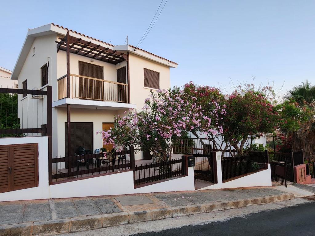 una casa con una valla y árboles delante de ella en Serena Vacation Home, en Pomos