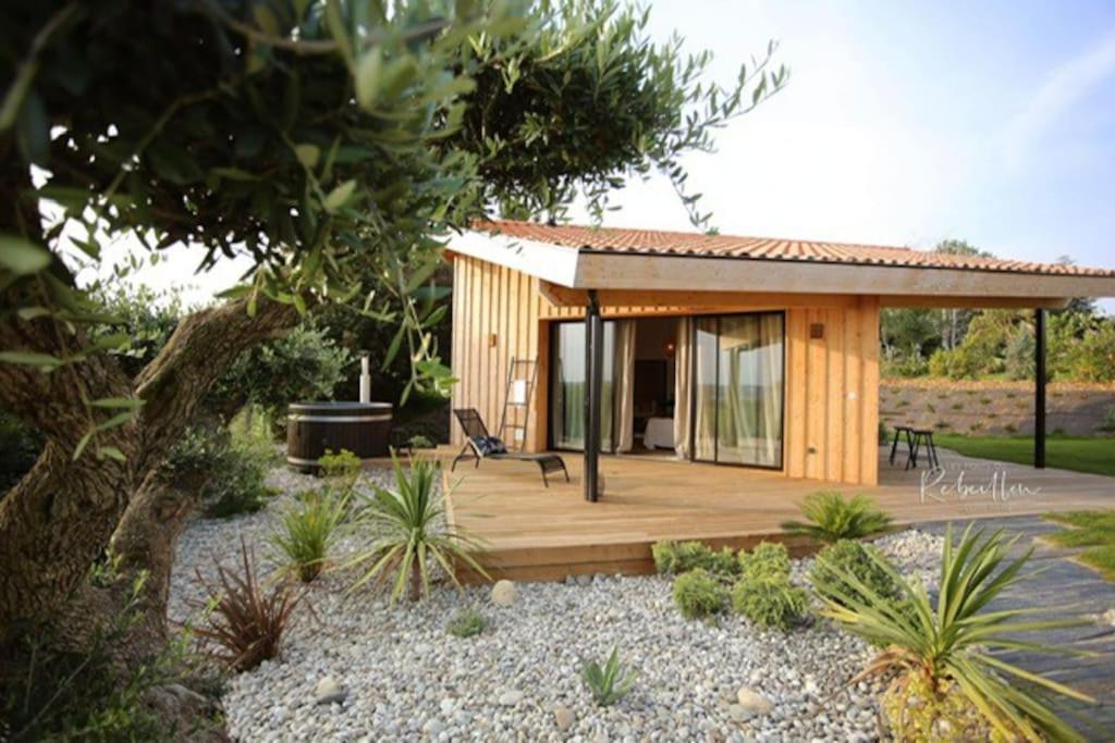 a small wooden cabin with a deck and a chair at les Hauts de Rébeillou - Cabane Spa in Flourens