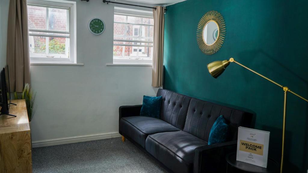 a living room with a black couch and a blue wall at Central Canterbury Apartment with Parking in Kent