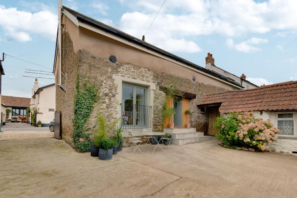 ein Backsteingebäude mit einem Tisch und Stühlen davor in der Unterkunft Kittiwake Cottage in Braunton