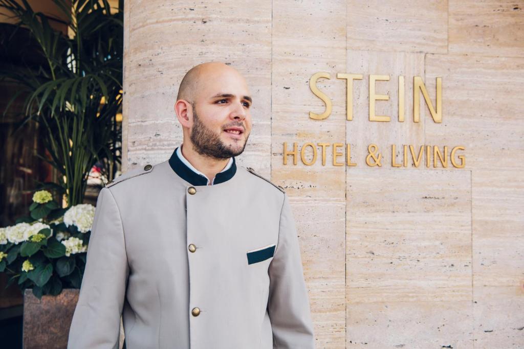 Ein Mann im Anzug, der vor einem Schild steht. in der Unterkunft Hotel Stein - Adults Only in Salzburg