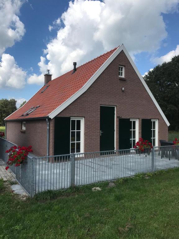 a red brick house with a white fence at De Dagloner in Nieuwlande
