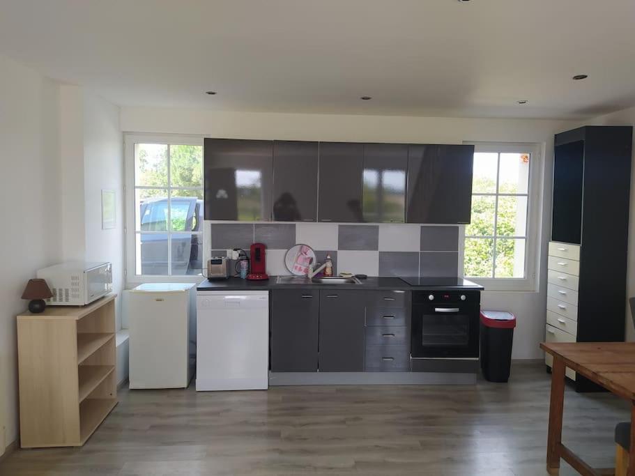 a kitchen with black cabinets and white appliances at Appart à la campagne in Marnefer