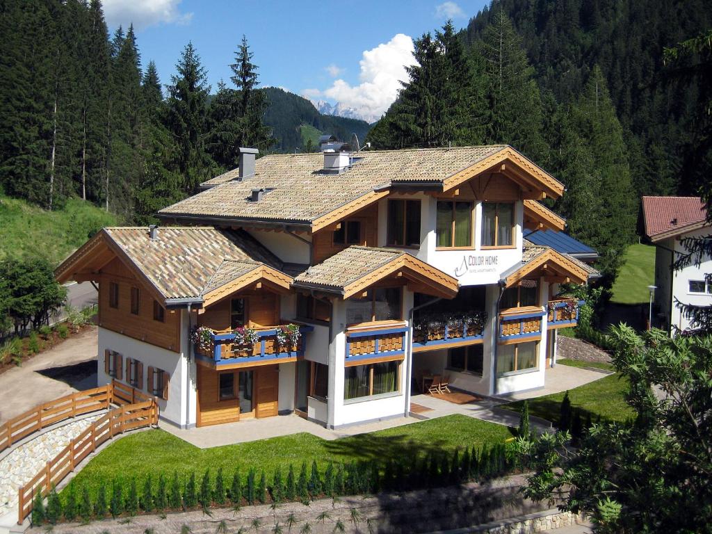 a large house in the middle of a forest at Color Home Suite Apartments in Predazzo