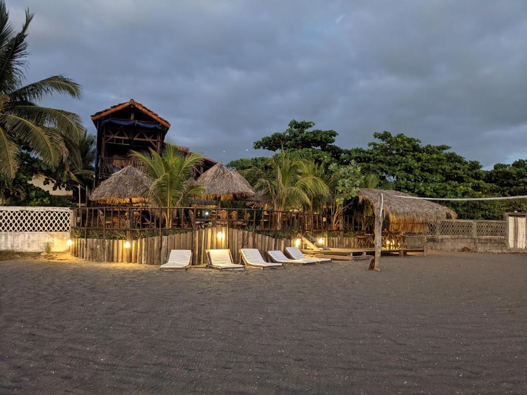 una fila di sedie a sdraio su una spiaggia di notte di Mano a Mano Eco Hostal a Las Peñitas