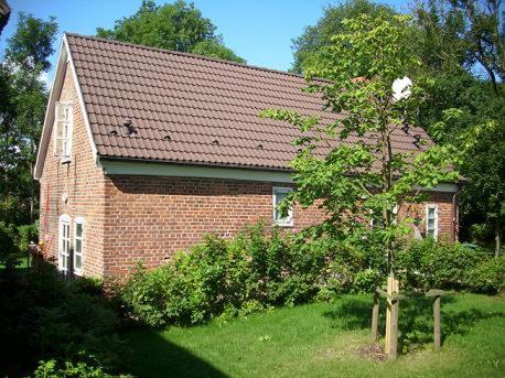 a red brick house with a tree in front of it at Altes Waschhaus in Putbus