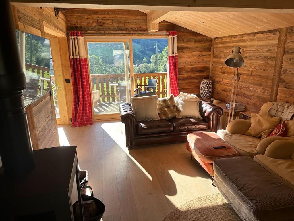 a living room with leather furniture and a large window at Chalet Flobelle in Entremont