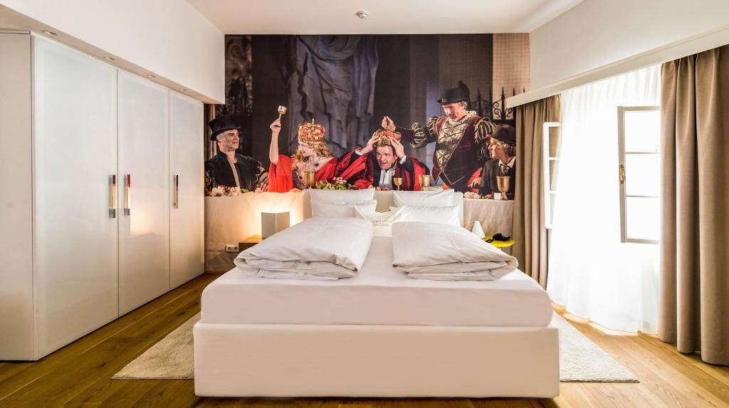 a white bed in a room with a painting on the wall at Small Luxury Hotel Goldgasse in Salzburg