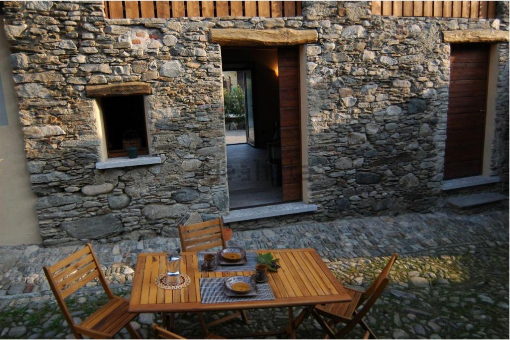 a wooden table and chairs in front of a stone building at Cà de sass 1891 in Vezzo