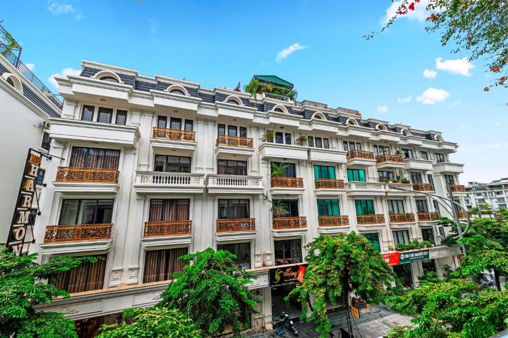 ein großes weißes Gebäude mit Bäumen davor in der Unterkunft Harmony HaLong Hotel in Hạ Long