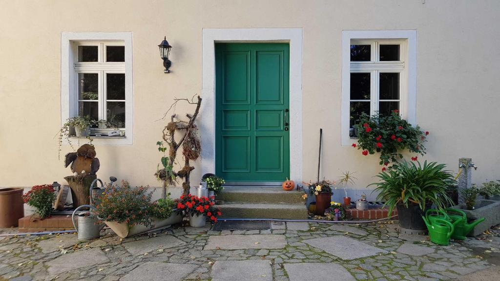 a green door on a house with potted plants at Loensches Gut in Görlitz