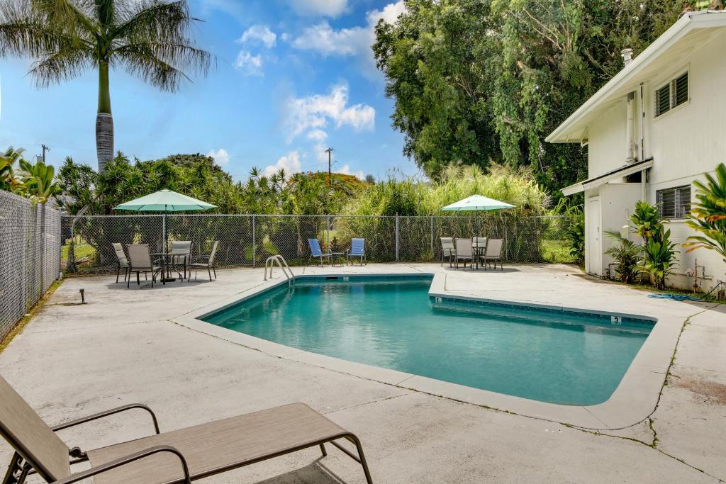 a swimming pool in a yard with chairs and umbrellas at Quaint Hilo Vacation Rental with Community Pool! in Hilo