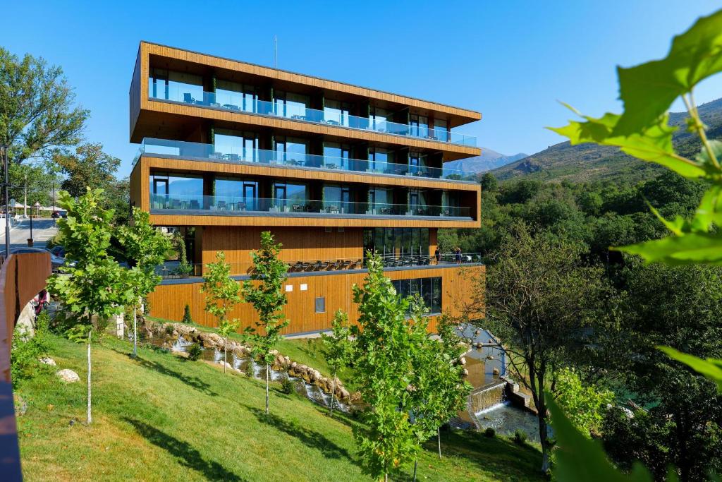 a building on a hill with trees in front of it at Hotel Uji Ftohte Tepelene in Tepelenë