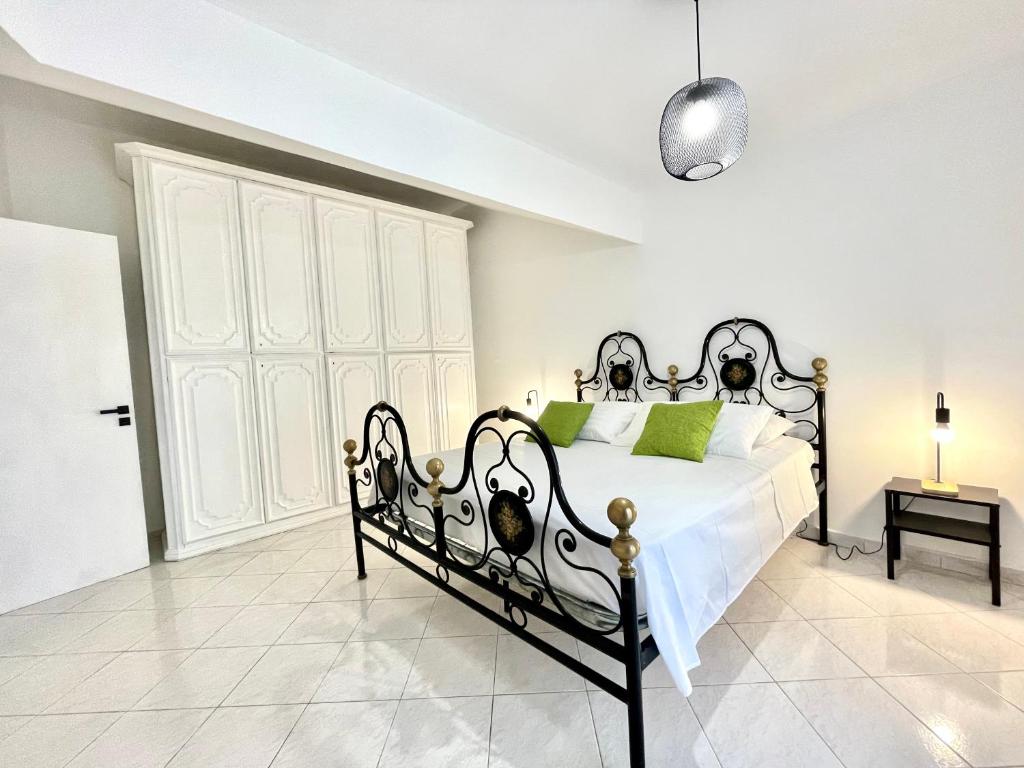 a bedroom with a black and white bed with green pillows at Defa Apartment in Giardini Naxos