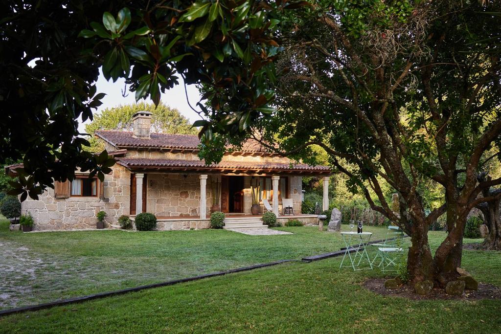 uma casa de pedra com uma árvore no quintal em CASA DO COMBRO em Ponteareas