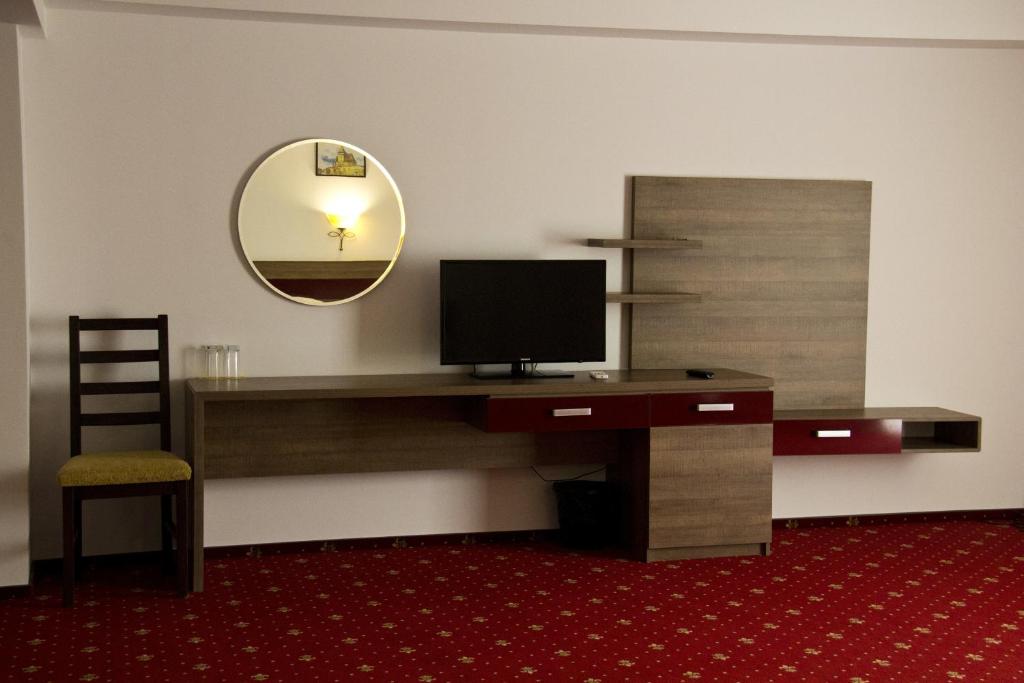 プロイェシュティにあるHotel City Ploiestiのデスク、テレビ、鏡が備わる客室です。