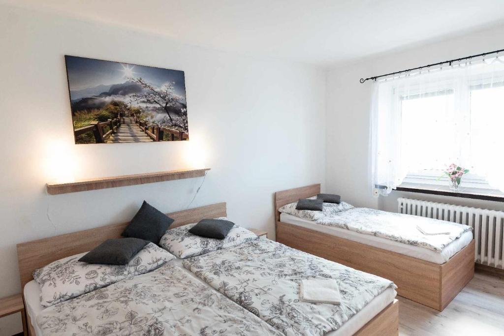 a bedroom with two beds and a painting on the wall at Apartmán LUKA in Buchlovice