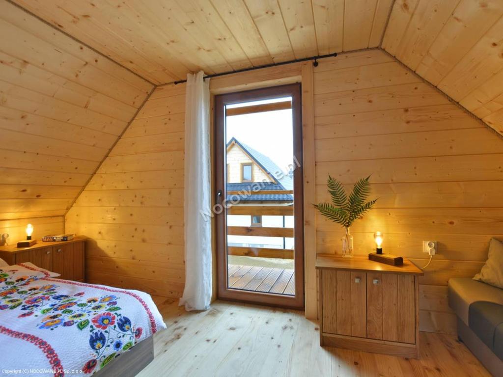 a bedroom with a bed and a large window at Ośrodek Wypoczynkowy Osada Solina in Ustrzyki Dolne