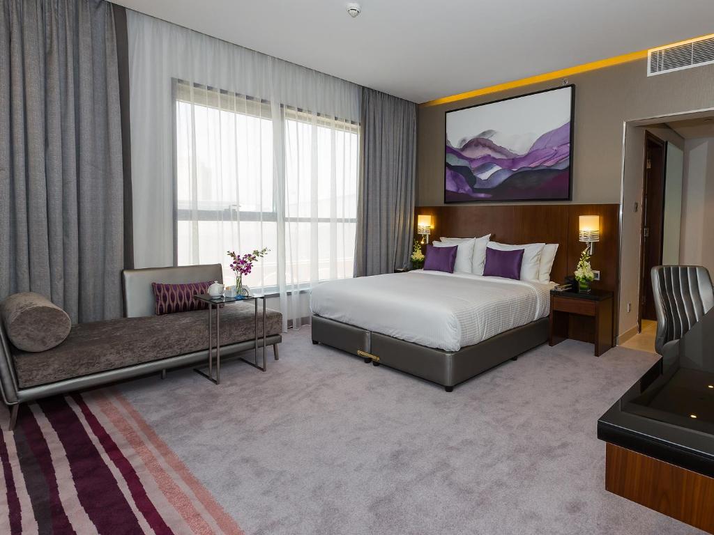 a hotel room with a bed and a television at Flora Al Barsha Hotel At The Mall in Dubai