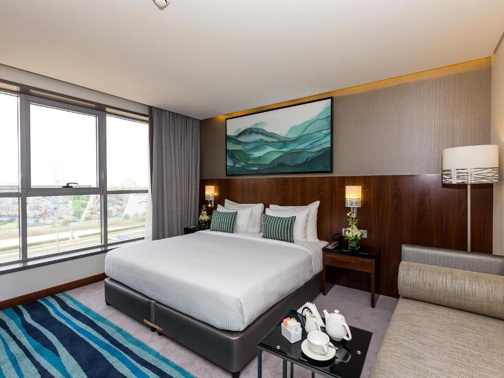 a hotel room with a bed and a couch at Flora Al Barsha Hotel At The Mall in Dubai