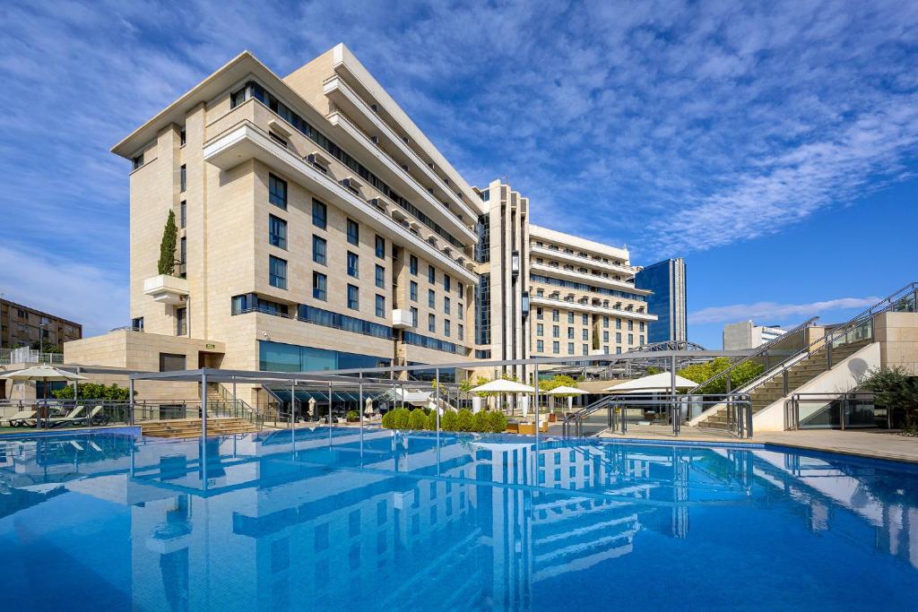 - un grand bâtiment avec une piscine en face dans l'établissement Hotel Nelva, à Murcie