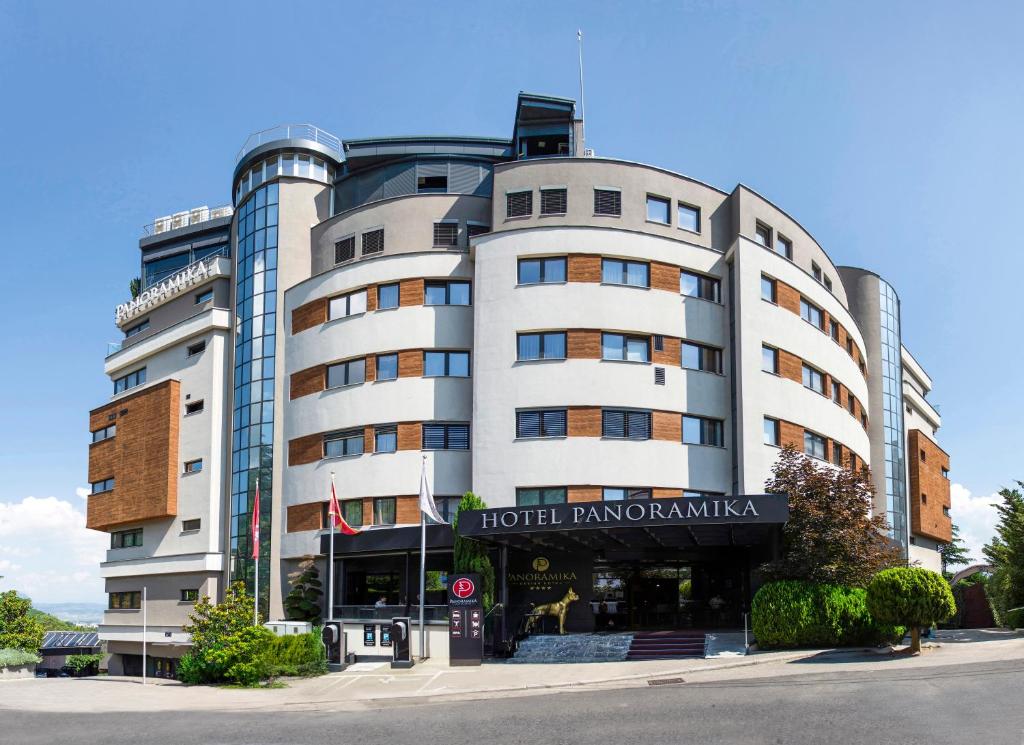 um grande edifício branco com um hotel em frente em Hotel Panoramika Design & Spa em Skopje