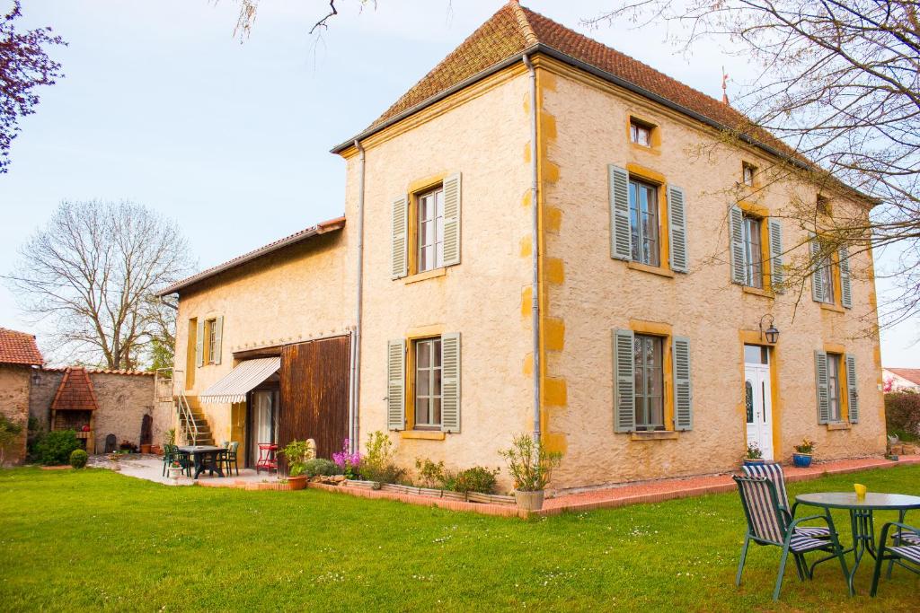 a house with a table and chairs in the yard at Aux Ronzières in Pouilly-sous-Charlieu