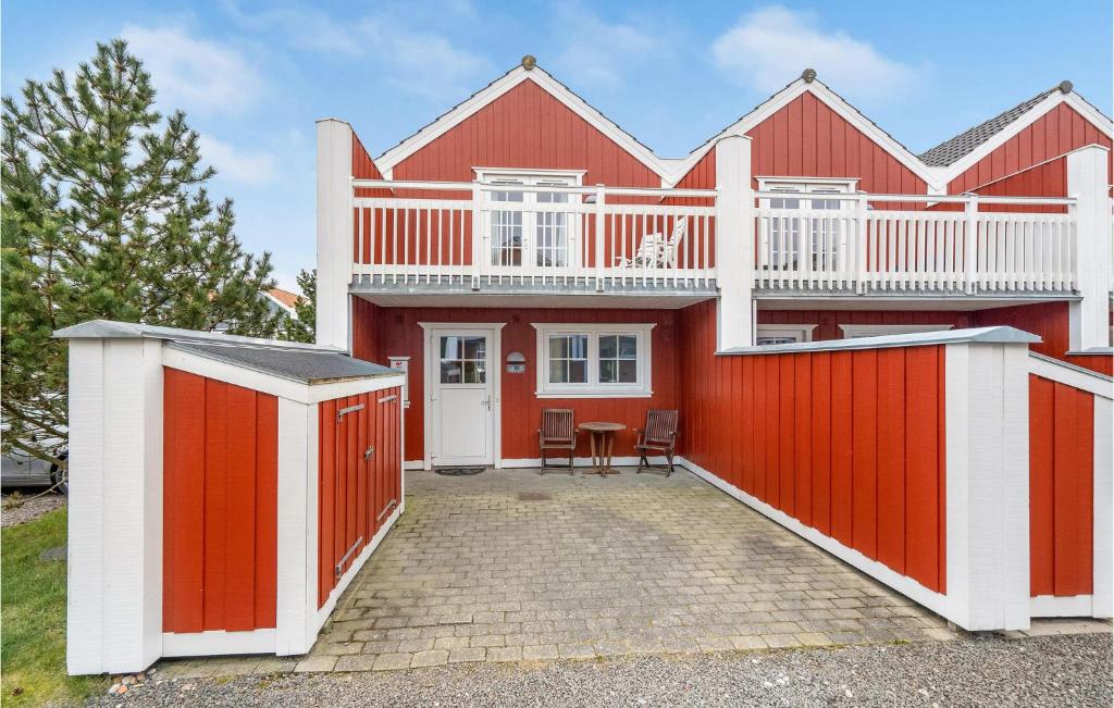 una casa roja y blanca con una valla en Stunning Home In Blvand With 2 Bedrooms, Sauna And Wifi, en Blåvand