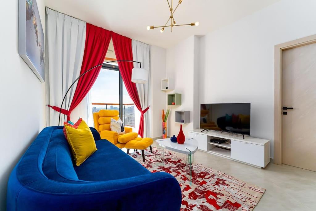 a living room with a blue couch and yellow chairs at Vibrant 2 Bedroom - E&G Homes in Dubai
