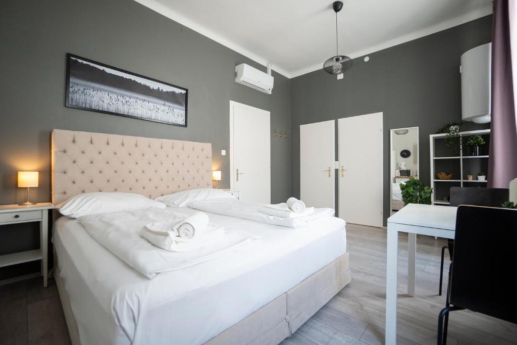 Un dormitorio con una gran cama blanca y una mesa en Bright ,cozy , central and cute studio in Vienna, en Viena