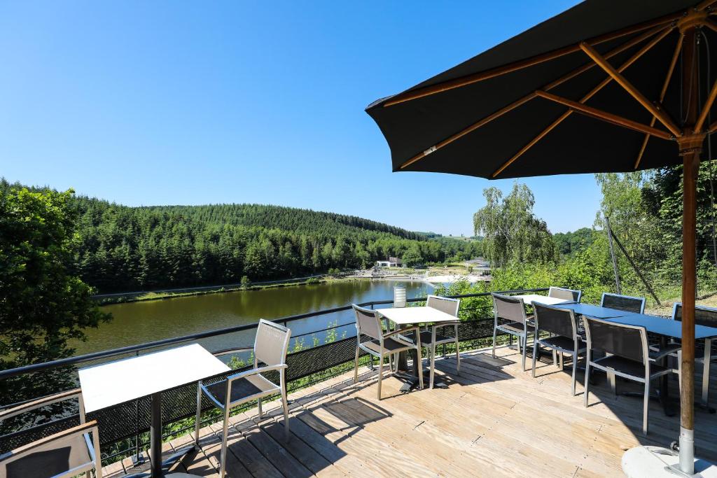 een terras met tafels en stoelen en uitzicht op een rivier bij Hotel Bô Rivage -- Eden-Ardenne in Neufchâteau