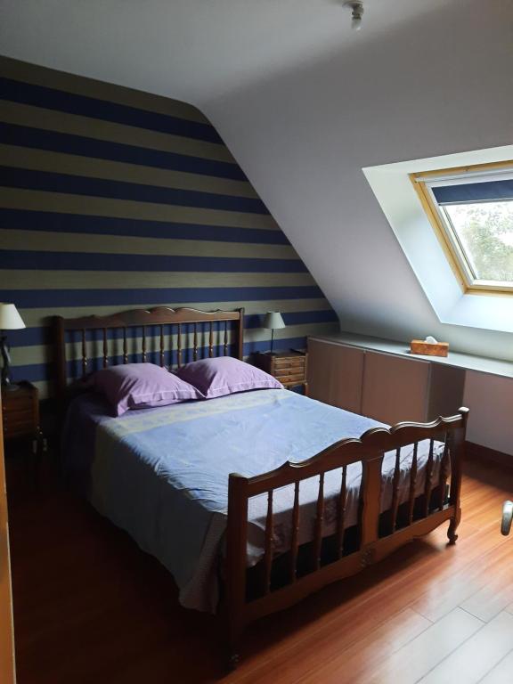 1 dormitorio con cama de madera y almohadas moradas en Chambre à louer, en Goven