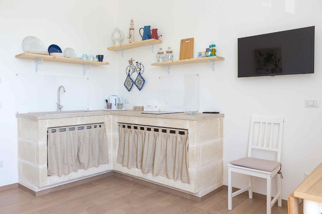 a kitchen with a sink and a tv on a wall at Boga & Vopa House in Savelletri di Fasano