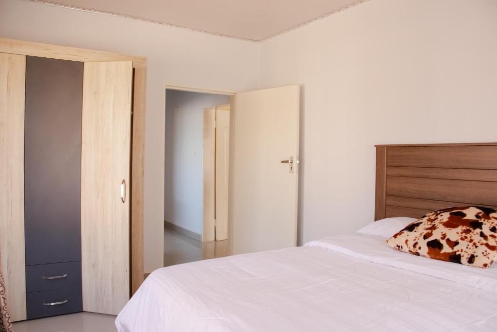 a bedroom with a white bed with a cow pillow at JRK Apartments & Services Limited in Lusaka