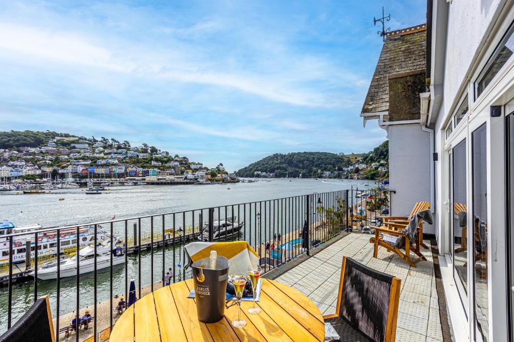 balcón con mesa y vistas al agua en Harbourside 3 - Luxury Riverside Apartment en Dartmouth
