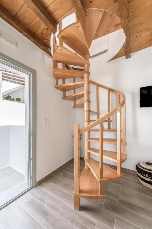 a wooden spiral staircase in a room with a window at Studios Betty in Plaka Milou