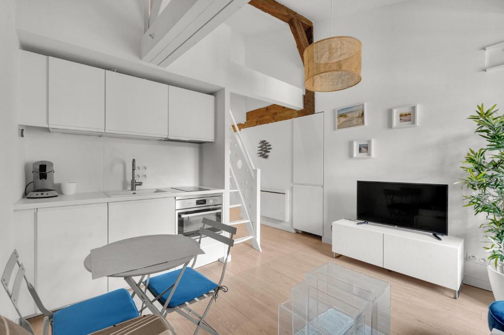 a kitchen with white cabinets and a table and chairs at Les Relais du Capitole - Appartements d'hôtes in Toulouse