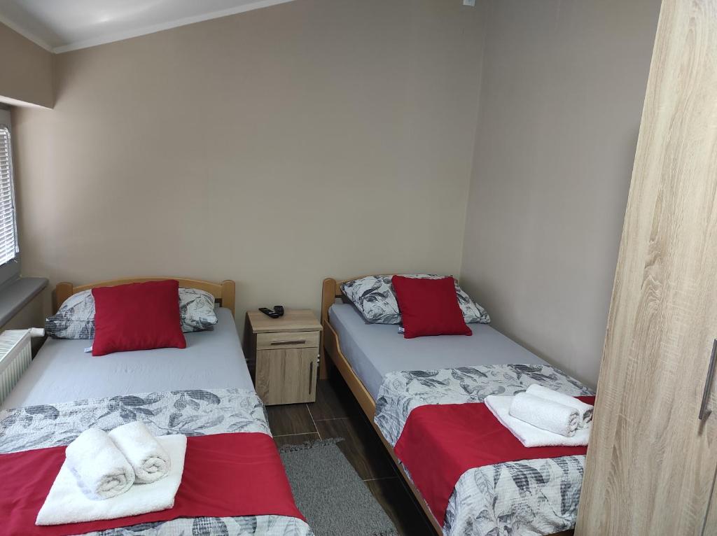 2 Betten in einem Zimmer mit roten und weißen Handtüchern in der Unterkunft Valor Apartmani Kikinda in Kikinda
