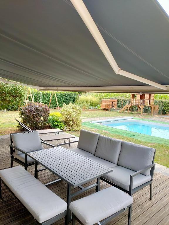 un patio con mesa, sillas y piscina en Maison au calme chez Djé et Lucie, en La Chapelle-dʼAligné
