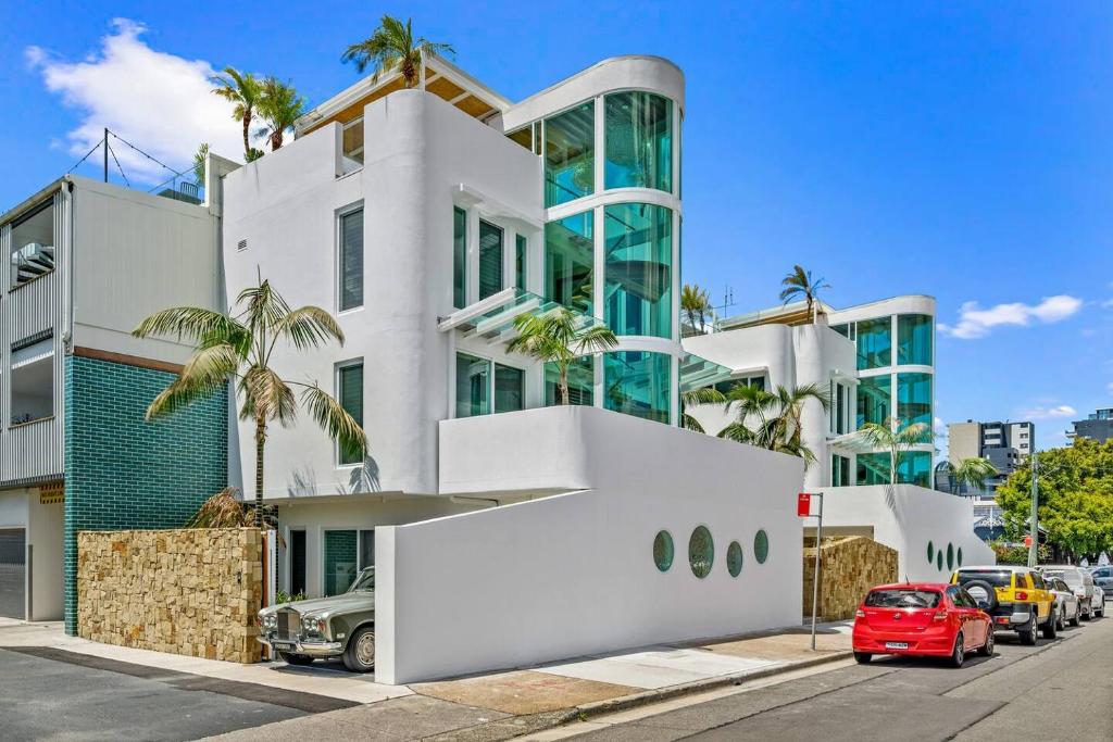 un bâtiment blanc avec une voiture rouge garée devant. dans l'établissement 'Harbour Lights' Iconic Maritime-inspired Living, à Wickham