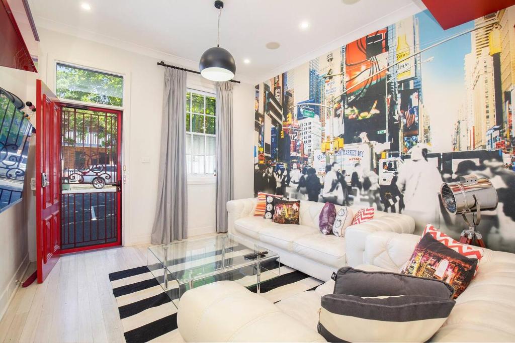 a living room with a white couch and a mural at Times Square Terrace - Vibrant Charm in Newy's Heart in Newcastle